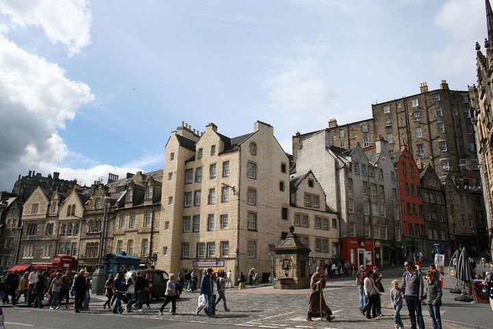 Tall old stone houses at the east end of the Grassmarket, with people crossing the cobbles.