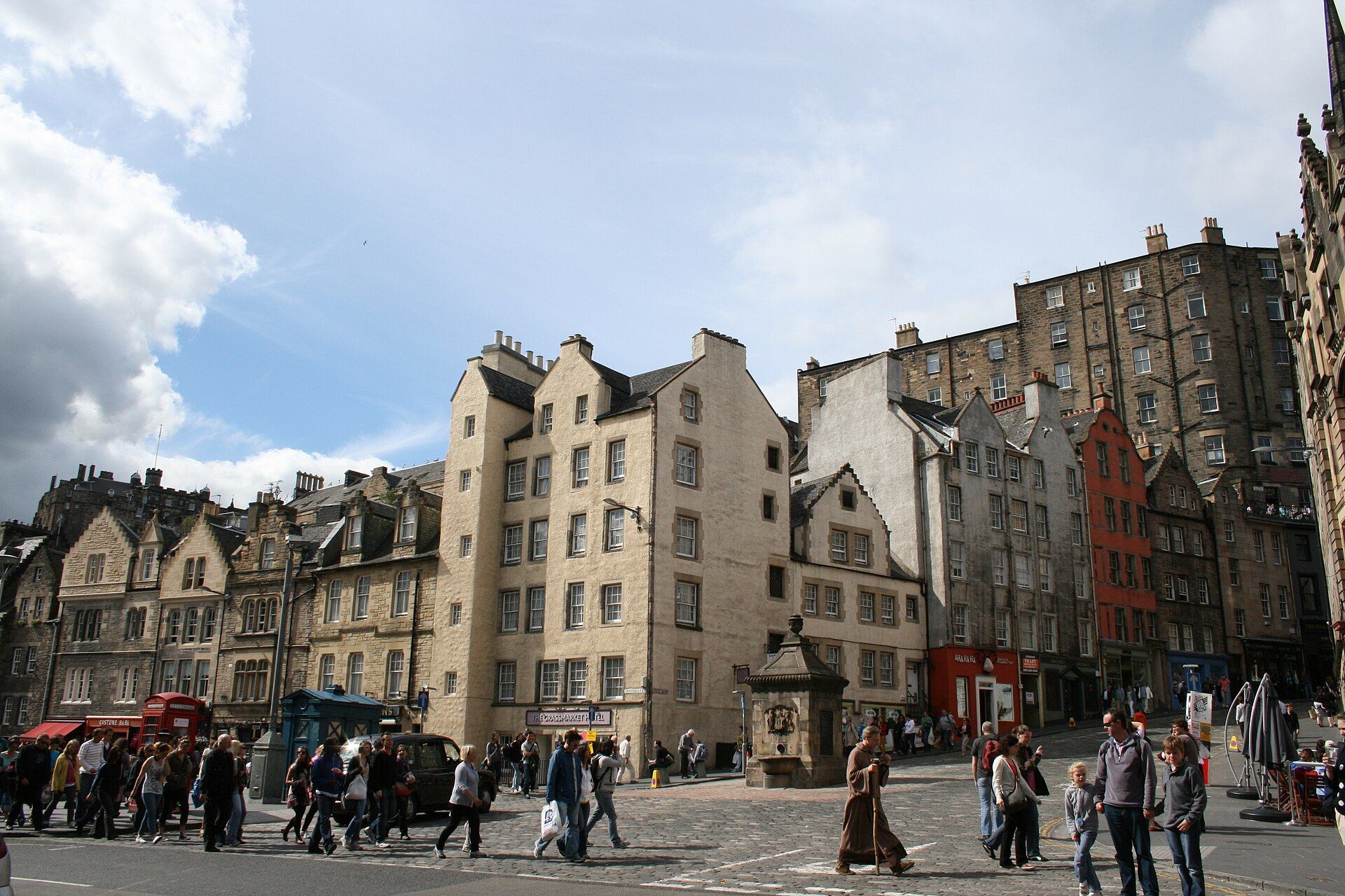 Tall old stone houses at the east end of the Grassmarket, with people crossing the cobbles.